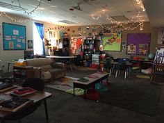 a classroom with lots of desks and chairs, lights strung from the ceiling above