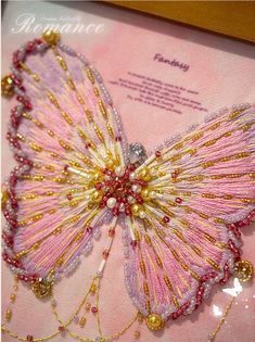 a pink and gold beaded butterfly in a frame