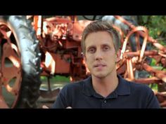 a man is standing in front of an old tractor and holding his hands out to the camera