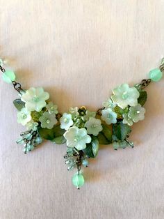 Pistachio Green Flower Necklace. Handbeaded with handpainted resin flowers and glass beads in a vee shape. This is a quality piece of jewelry that will last a life time. Created by designer Colleen Toland who has been creating her unique style of vintage jewelry for more than 30 years. All of our pieces come with an engraved tag with Colleen's name so as you know you are receiving authentic Colleen Toland jewelry. Necklace measures 20 inches with a 4 inch extender so as you can change the length Artisan Green Hand Painted Necklaces, Artisan Green Hand Painted Necklace, Artisan Hand Painted Green Necklace, Green Hand Painted Artisan Necklace, Green Beaded Flower Pendant Jewelry, Green Resin Necklaces For Jewelry Making, Green Resin Flower Jewelry, Green Jade Flower Necklace, Whimsical Green Flower Jewelry