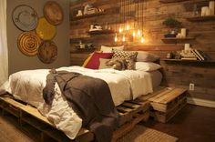 a bed made out of wooden pallets with lights hanging from the ceiling above it