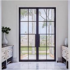 an empty room with large windows and white furniture in front of the doors that lead to a yard