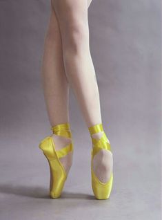 a woman in yellow ballet shoes posing for the camera with her legs crossed and one leg bent