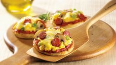 mini pizzas with pepperoni and cheese are on a wooden tray