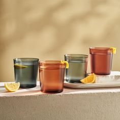 three glasses sitting on top of a table with lemon wedges