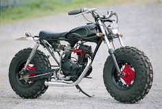 a black and red motorcycle parked on top of a gravel road