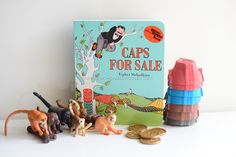 a book and toy animals sitting on a table next to stacks of books with caps for sale written on them