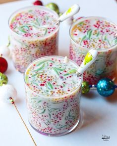 three glasses filled with liquid sitting on top of a white table next to christmas decorations