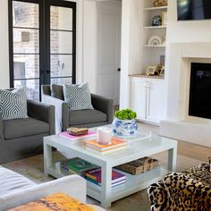 a living room with two couches and a table in front of a tv mounted on the wall