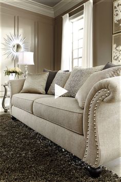 a living room filled with furniture and a large mirror on the wall above it's headboard