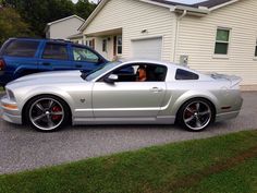 a silver mustang parked in front of a house