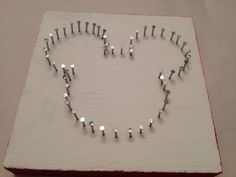 a heart made out of silver beads on top of a white board with red trim