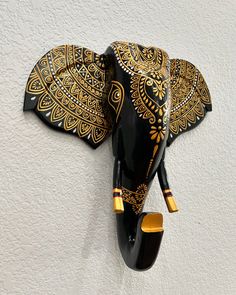 an elephant head mounted to the side of a white wall with gold designs on it