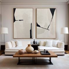 a living room with two paintings on the wall and a coffee table in front of it