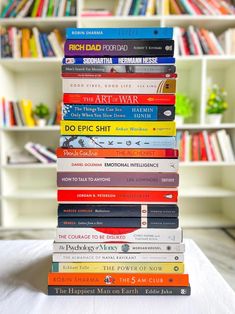 a stack of books sitting on top of a bed in front of a book shelf