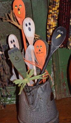 an image of halloween decorations made out of wooden spoons and fake pumpkin faces in a bucket