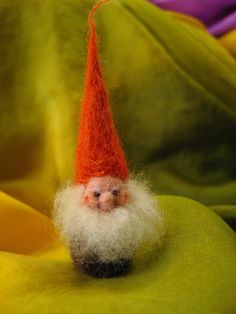 an orange and white gnome's head on top of a green cloth covered surface