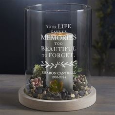 a glass vase with a candle and succulents in it that says your life gave us memories too beautiful to forget