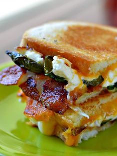 a close up of a sandwich on a green plate with bacon, cheese and spinach