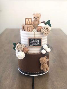 a baby shower cake with teddy bears and flowers on the top, sitting on a wooden table