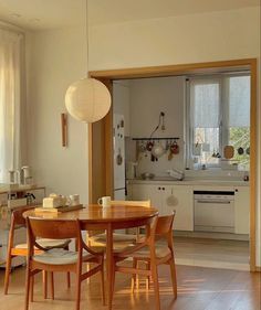 an open kitchen and dining room with wood floors, white walls and cabinets in the background