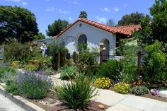 a white house surrounded by trees and flowers