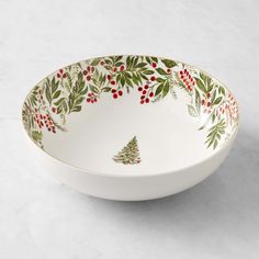 a white bowl with holly and red berries on the rim is sitting on a marble surface