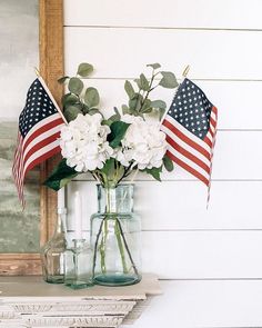 flowers in a vase with an american flag on the mantle