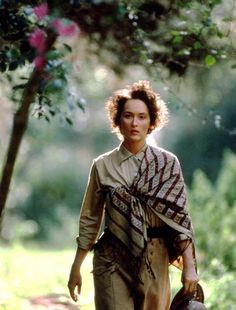 a woman walking in the woods carrying a purse