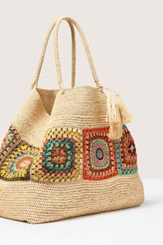 a straw bag with multicolored beads and tassels on the handle, sitting on a white surface