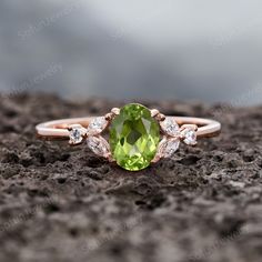 an oval cut peridot and diamond engagement ring on top of a rocky surface