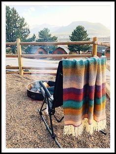 a blanket is hanging on the back of a chair in front of a fire pit