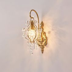 a wall light that is on the side of a wall with crystal beads hanging from it