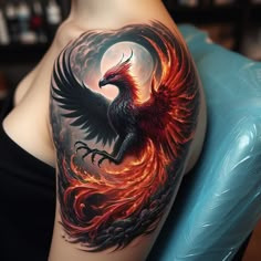 a woman with a tattoo on her arm has a red and black fire bird on it's shoulder