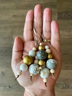 a hand holding several different colored beads in it's palm with gold and silver accents