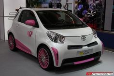 a white and pink smart car is on display