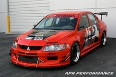 a red car with black and white stripes parked in front of a garage