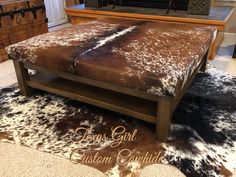 a brown and white cowhide rug on top of a wooden bed frame in a living room