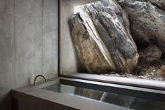 a large rock sitting next to a window in a room with concrete walls and flooring