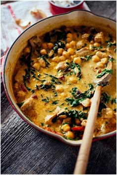 a pan filled with chickpeas and spinach on top of a wooden table