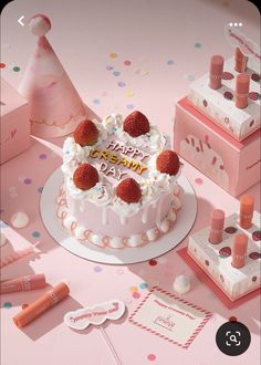 a pink birthday cake with strawberries on top surrounded by confetti and decorations