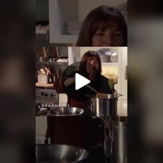 a woman standing in a kitchen next to pots and pans