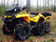 a yellow four - wheeler parked in the woods with its front tires up and out