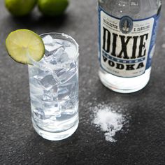 two bottles of vodka with limes and salt on the table next to each other