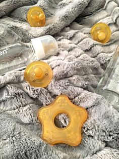 two baby pacifiers and an empty bottle on a gray blanket with grey flannel