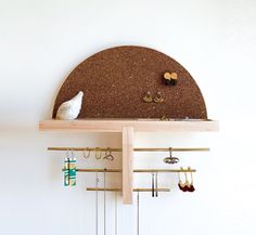 a white bird sitting on top of a wooden shelf filled with earrings and earring hooks