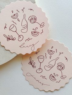 two paper tags with drawings on them sitting next to each other, one is pink and the other has red ink