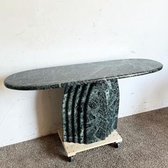 a green marble table sitting on top of a wooden stand next to a white wall