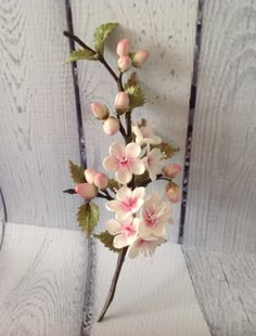 a white and pink flower arrangement on a wooden table next to a gray painted wall