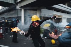 a protester wearing a yellow hard hat and holding a fire extinguisher